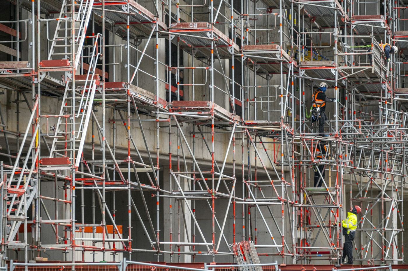 Modulgerüst mit Treppenaufgängen an einem Rohbau, Gerüstbauer bei der Montage